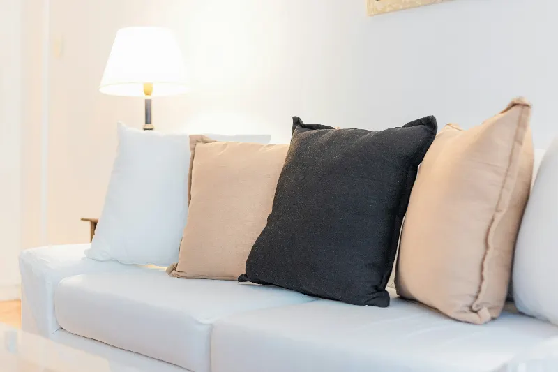 Linnekuddar i vitt, beige och svart i en ljus soffa